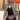 Femme en hijab pied-de-poule Infinity Mimi Kiseki, photographiée de profil en extérieur, portant une abaya noire élégante et un sac arrondi beige, style raffiné et urbain.