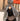 Femme en hijab pied-de-poule Infinity Mimi Kiseki, photographiée de profil en extérieur, portant une abaya noire élégante et un sac arrondi beige, style raffiné et urbain.