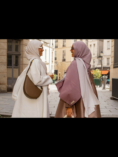 Deux femmes élégantes en hijab discutent dans une rue parisienne, habillées avec les créations Mimi Kiseki, dans un style minimaliste et raffiné.