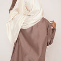 Femme de dos vêtue d’un hijab en soie écru Mimi Kiseki, au tombé fluide et lumineux, symbole de douceur, de pureté et d’élégance naturelle.