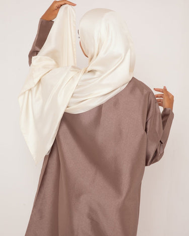 Femme de dos vêtue d’un hijab en soie écru Mimi Kiseki, au tombé fluide et lumineux, symbole de douceur, de pureté et d’élégance naturelle.